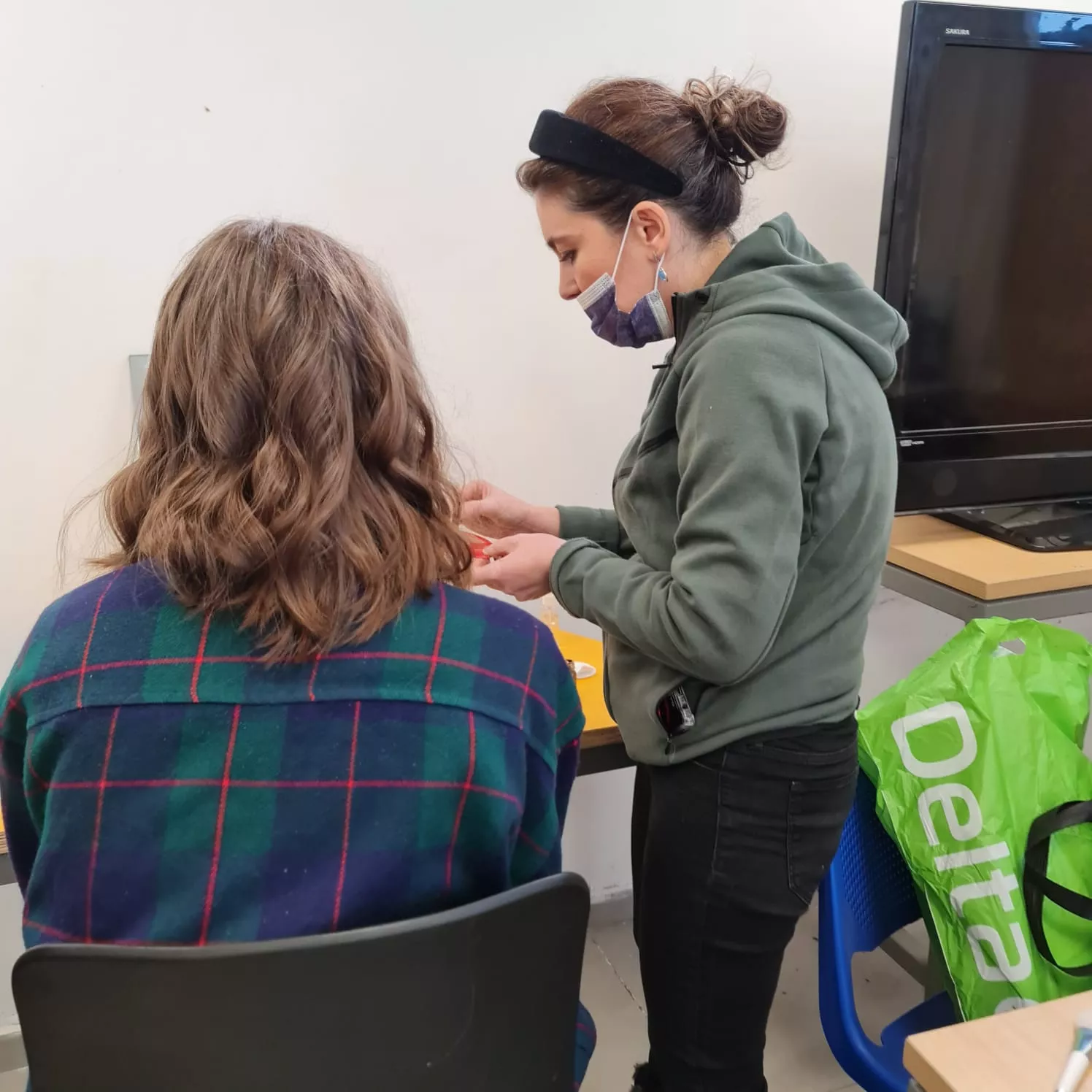 סטודנטית בקורס עיצוב שיער מקבלת הדרכה על החלקות שיער, עם דגש על טכניקות מתקדמות.