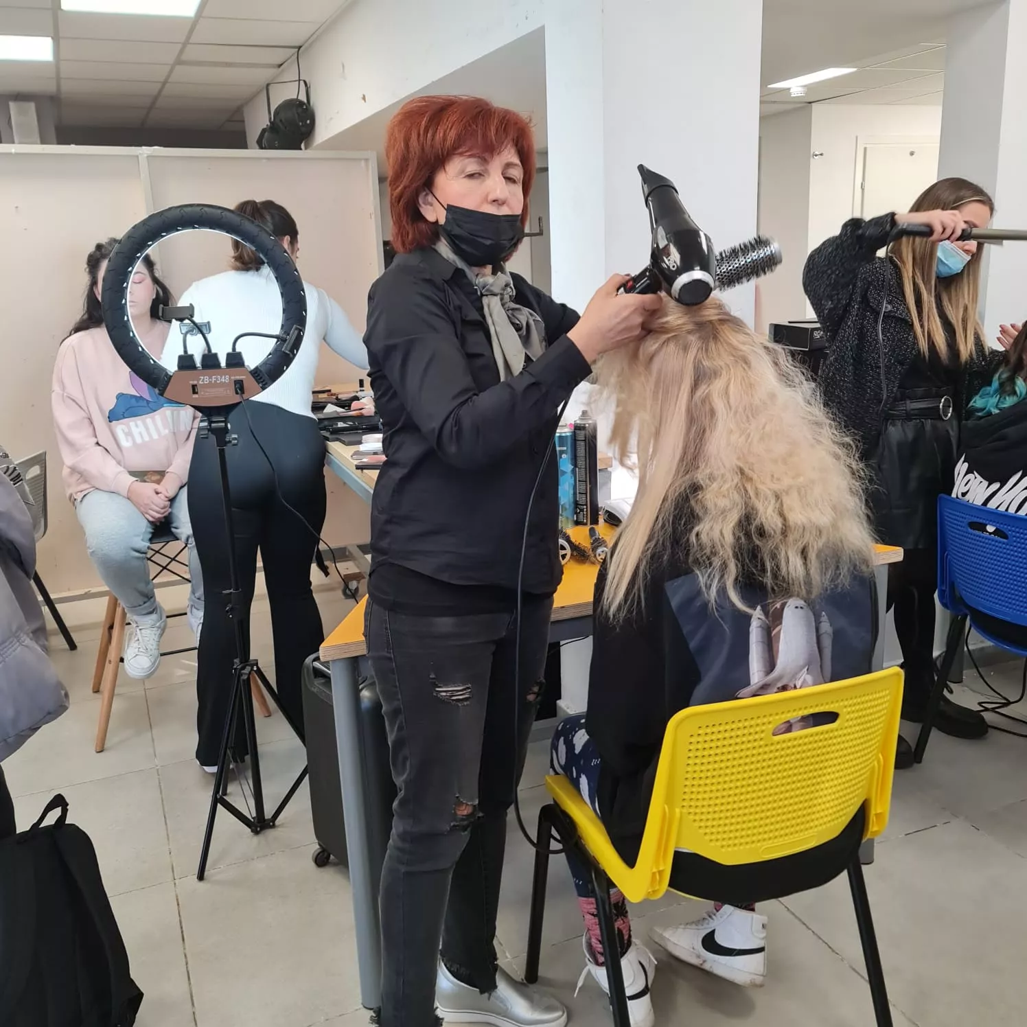 לימודי עיצוב שיער: אישה מעצבת שיער ללקוחה בסדנת קורס ספרות בבית ספר לספרות.