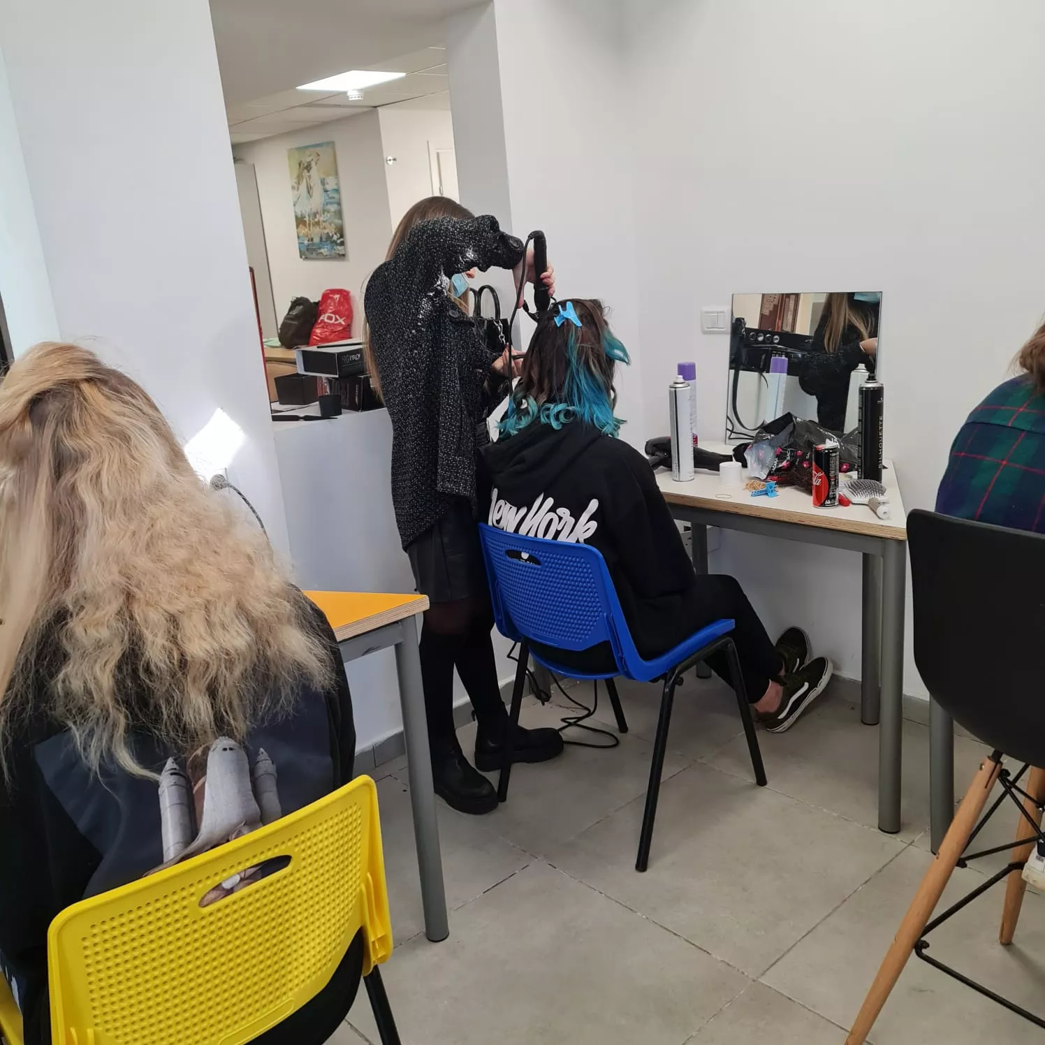 סטודנטיות בלימודי עיצוב שיער מתעסקות בעבודת תסרוקות, בכיתה בבית ספר מקצועי.