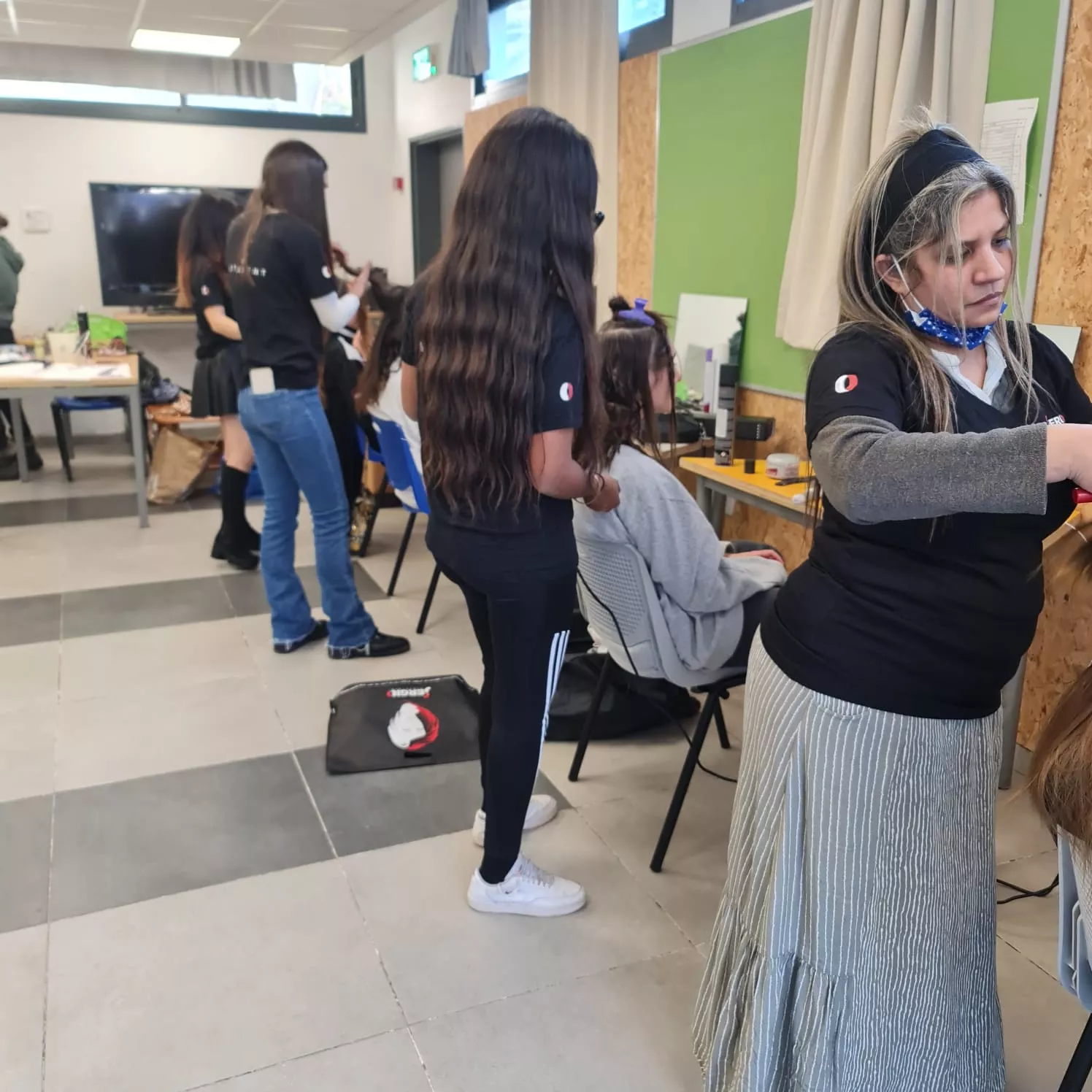 בכיתה ללימודי עיצוב שיער, תלמידות מתנסות בטכניקות שונות על לקוחות.