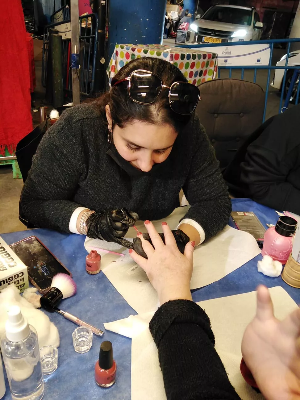 אישה מבצעת מניקור עם לק ג'ל, ציוד למניקור פדיקור סביב, בסביבה מקצועית.