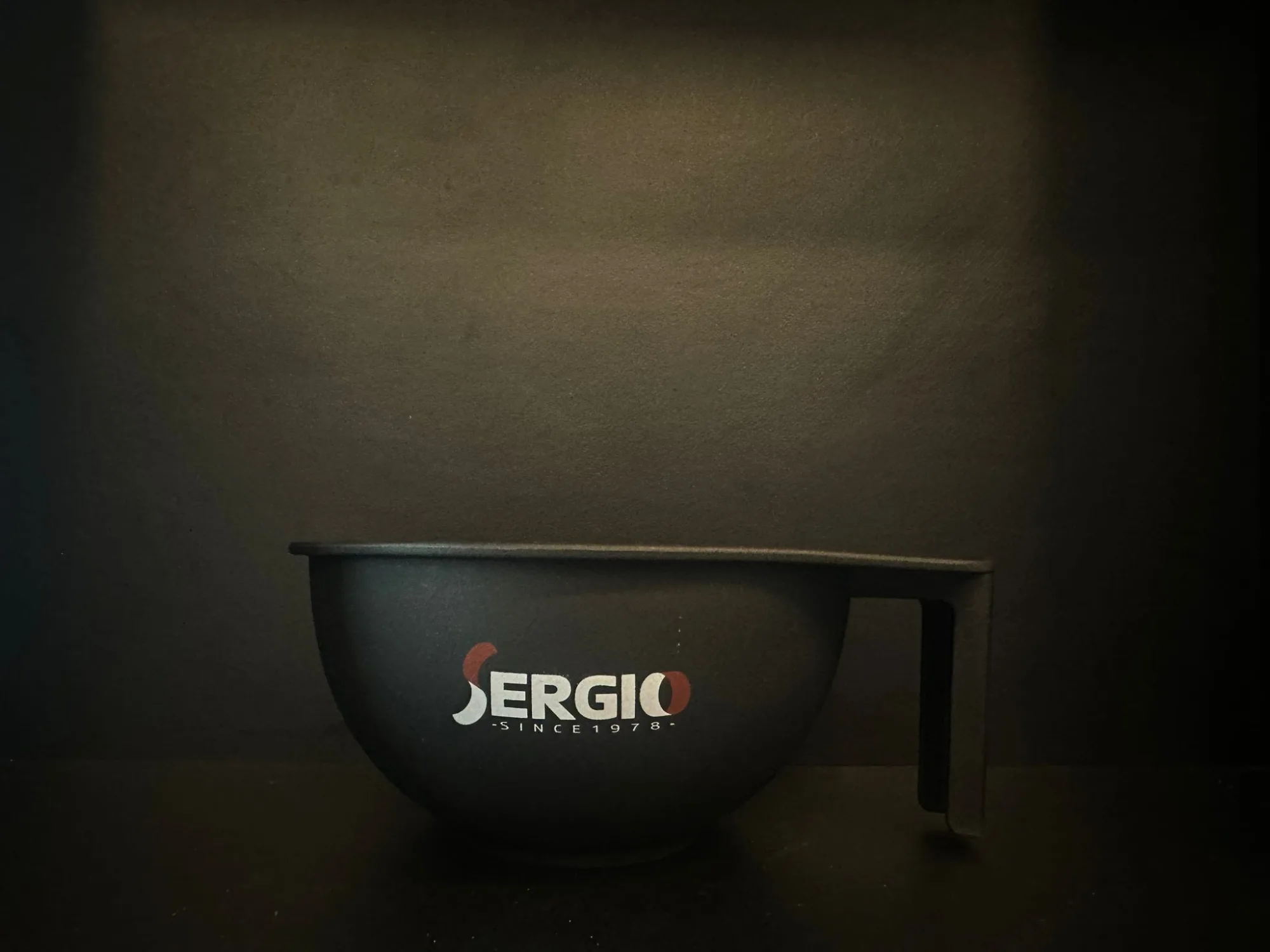 קערת צבע לשיער עם לוגו של SERGIO על רקע כהה. אידיאלית לקורסי עיצוב שיער.