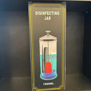 צנצנת חיטוי עם כלי מספריים ומברשות, מתאימה לשימוש במספרות ובמכוני יופי.